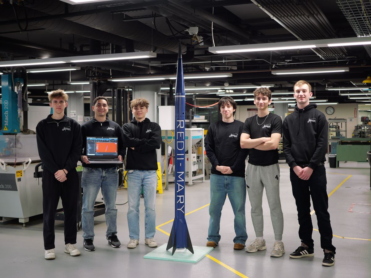 Kevin Polanco and five members of the simulations team standing around the finished RED II Mary vehicle, Kevin holding a laptop showing the CFD result.