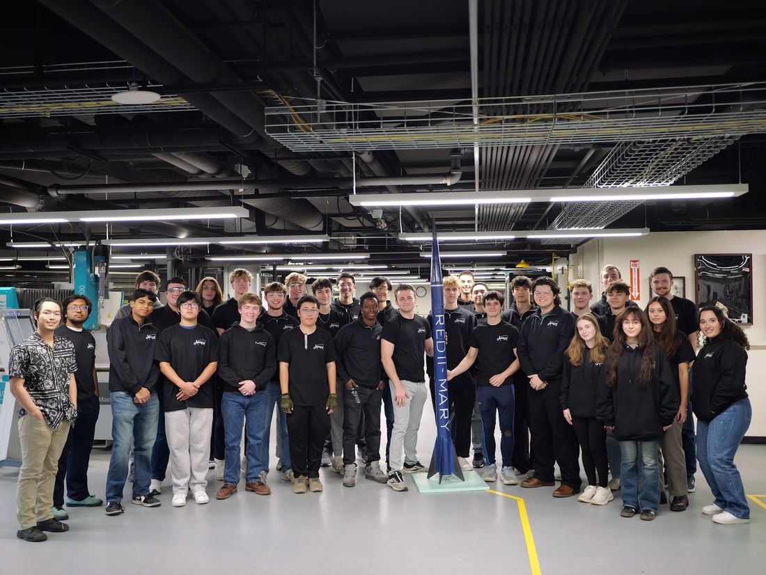 The full AeroBing Rocketry Research Group, around twenty five members, gathered around the vehicle in the machine shop.