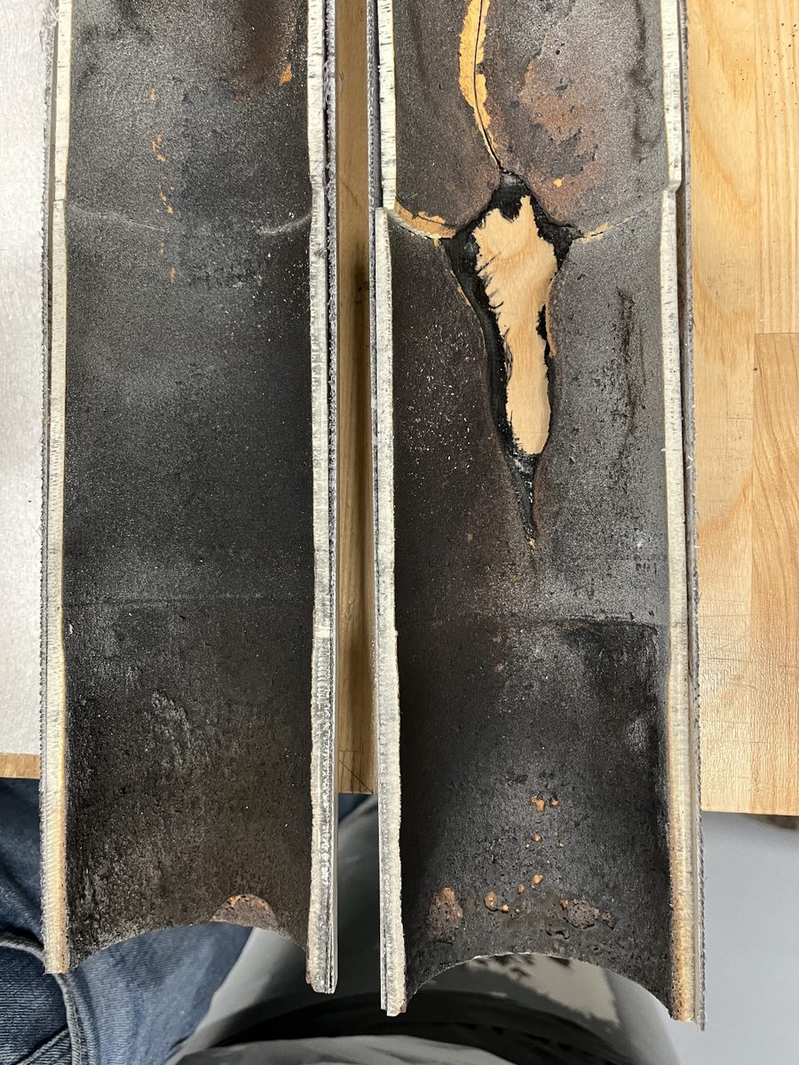 A sectioned rocket motor casing showing the charred and burned-through HTPB insulation liner inside.